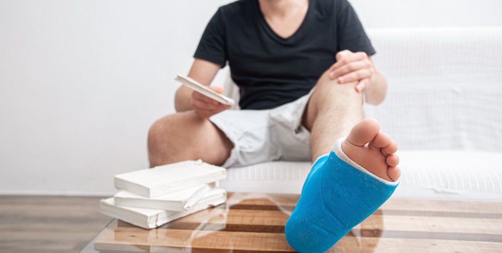 Close up man's broken leg in blue splint for treatment of injuries from ankle sprain at home.