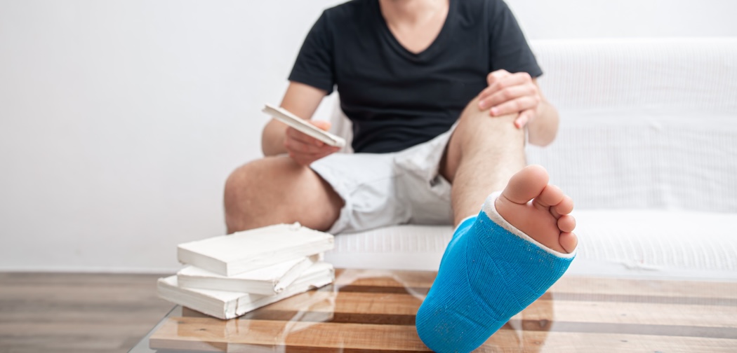 Close up man's broken leg in blue splint for treatment of injuries from ankle sprain at home.